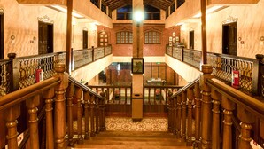 A grand staircase with wooden balusters and a tiled floor, leading to an upper level with a view of the outside. - Casa Severina (Calangute)