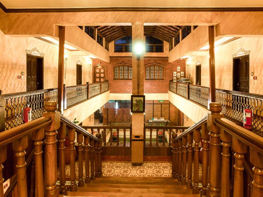A grand staircase with wooden balusters and a tiled floor, leading to an upper level with a view of the outside.