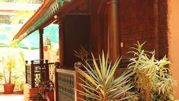 A building with a tiled roof, a porch with a railing, and several potted plants.