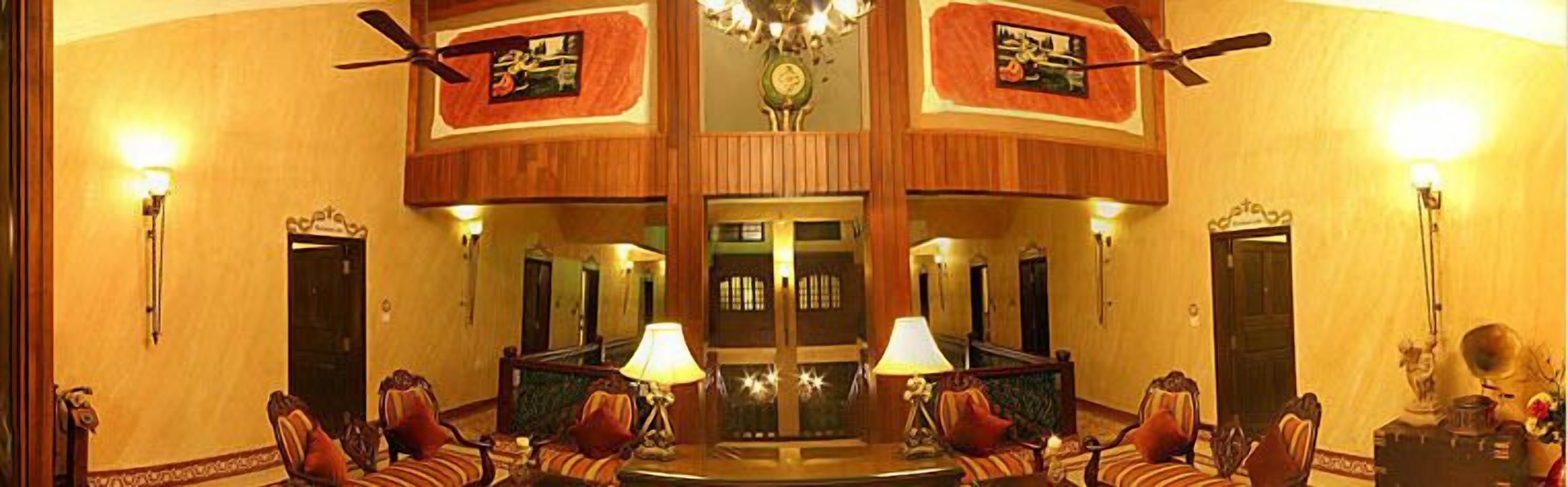 A lobby with a central seating area, two doors, and ceiling fans.