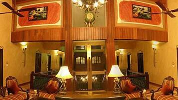 A lobby with a central seating area, two doors, and ceiling fans.