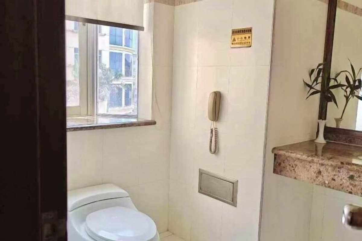 Ein kleines Badezimmer mit Toilette, Telefon und Fenster.