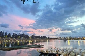 Un lac paisible où sont amarrés des bateaux, un ciel dégagé et, au loin, la silhouette d’une ville.