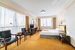 A hotel room with a bed, desk, chairs, and a TV. - General Fenghua (Xiamen) Resort Center (Xiamen)