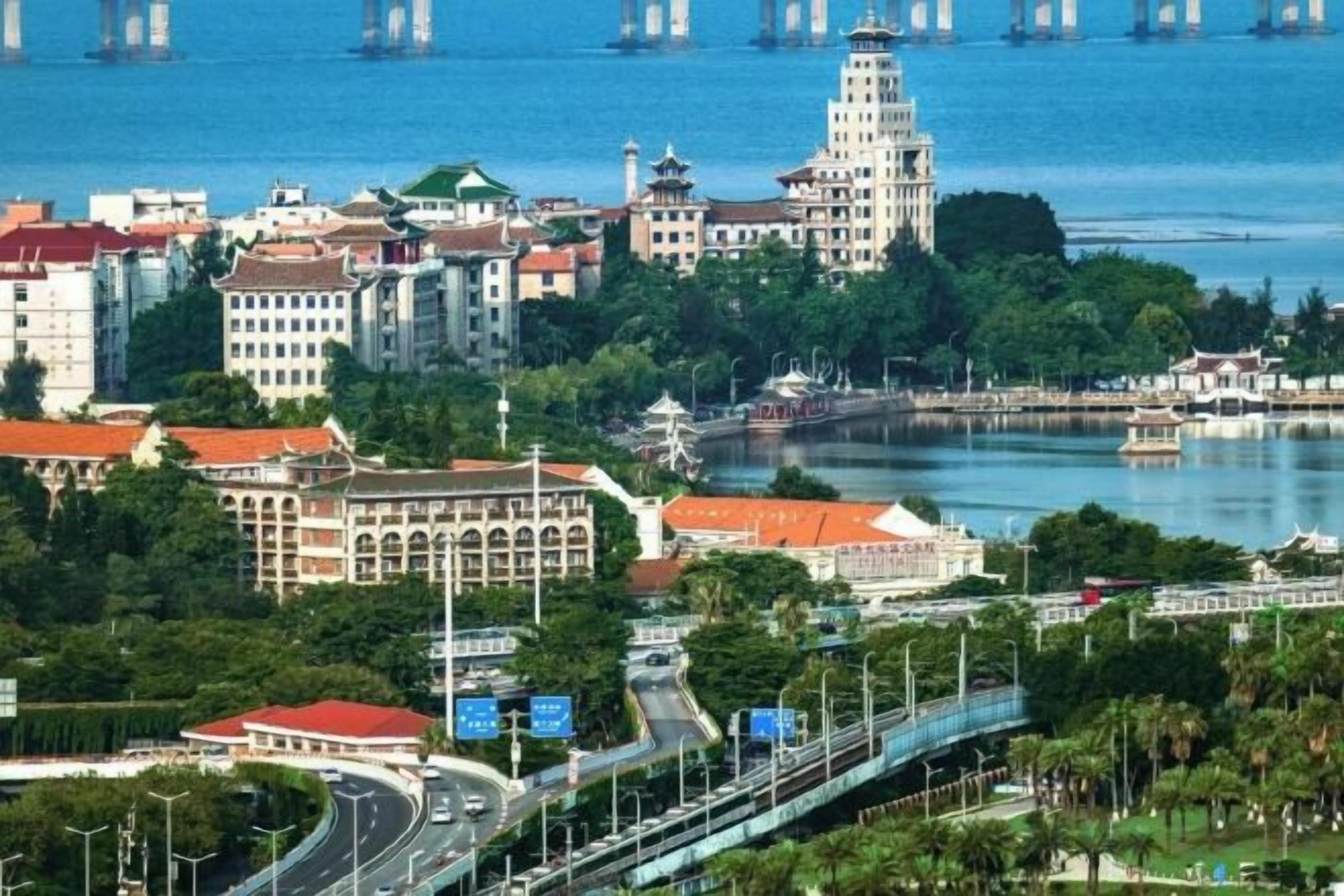 A coastal cityscape with a prominent tower, a bridge, and a river.