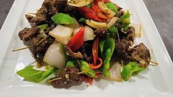 A dish of skewered meat with vegetables on a white plate.