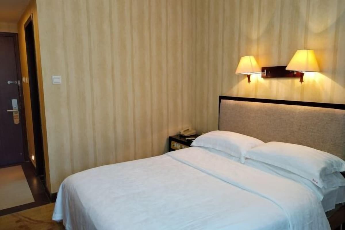 Ein Hotelzimmer mit einem Bett, zwei Wandleuchten, einem Nachttisch und einer Tür.