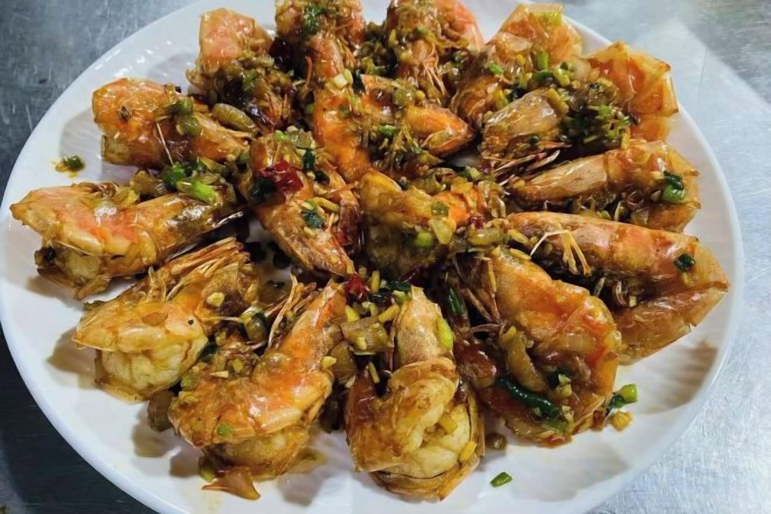 Une assiette de crevettes cuites, garnie d’herbes et d’épices.