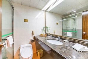Ein modernes Badezimmer mit großem Spiegel, zwei Waschbecken, Toilette und einer Duschkabine aus Glas.