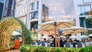 An outdoor dining area with multiple umbrellas, a reception desk, and a modern building in the background. - The Langham, Shanghai, Xintiandi (Shanghai)