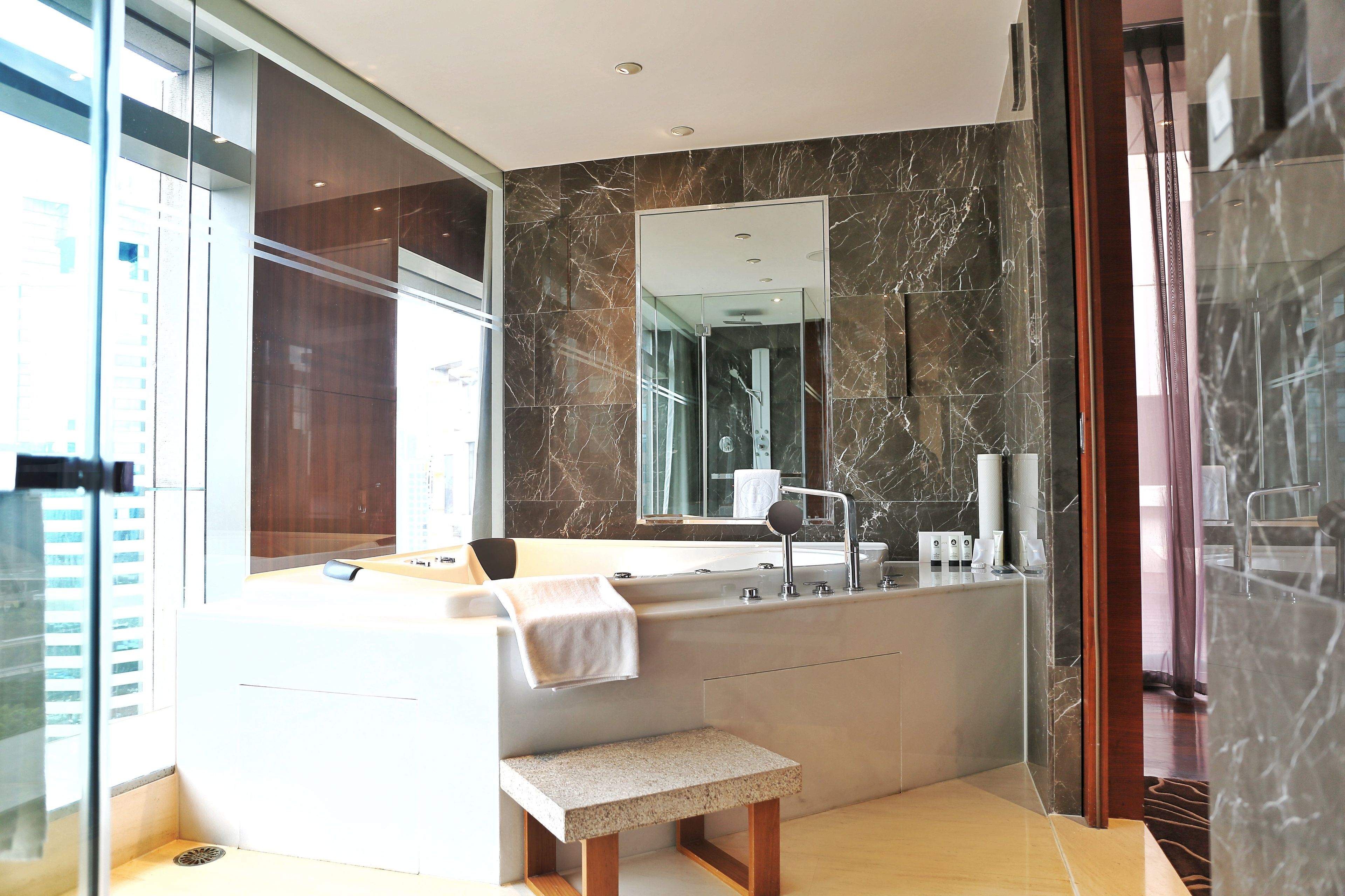A modern bathroom with a large mirror, a bathtub, and a shower.