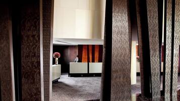 A reception area with a receptionist desk, patterned columns, and a carpeted floor.