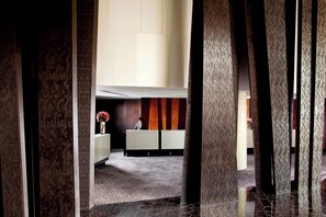 A reception area with a receptionist desk, patterned columns, and a carpeted floor.