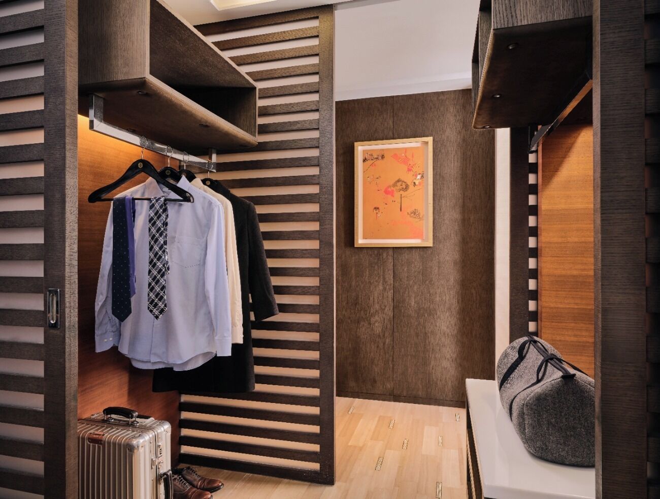 A modern, compact room with a wooden slat partition, a framed artwork on the wall, and a seating area with a cushion.