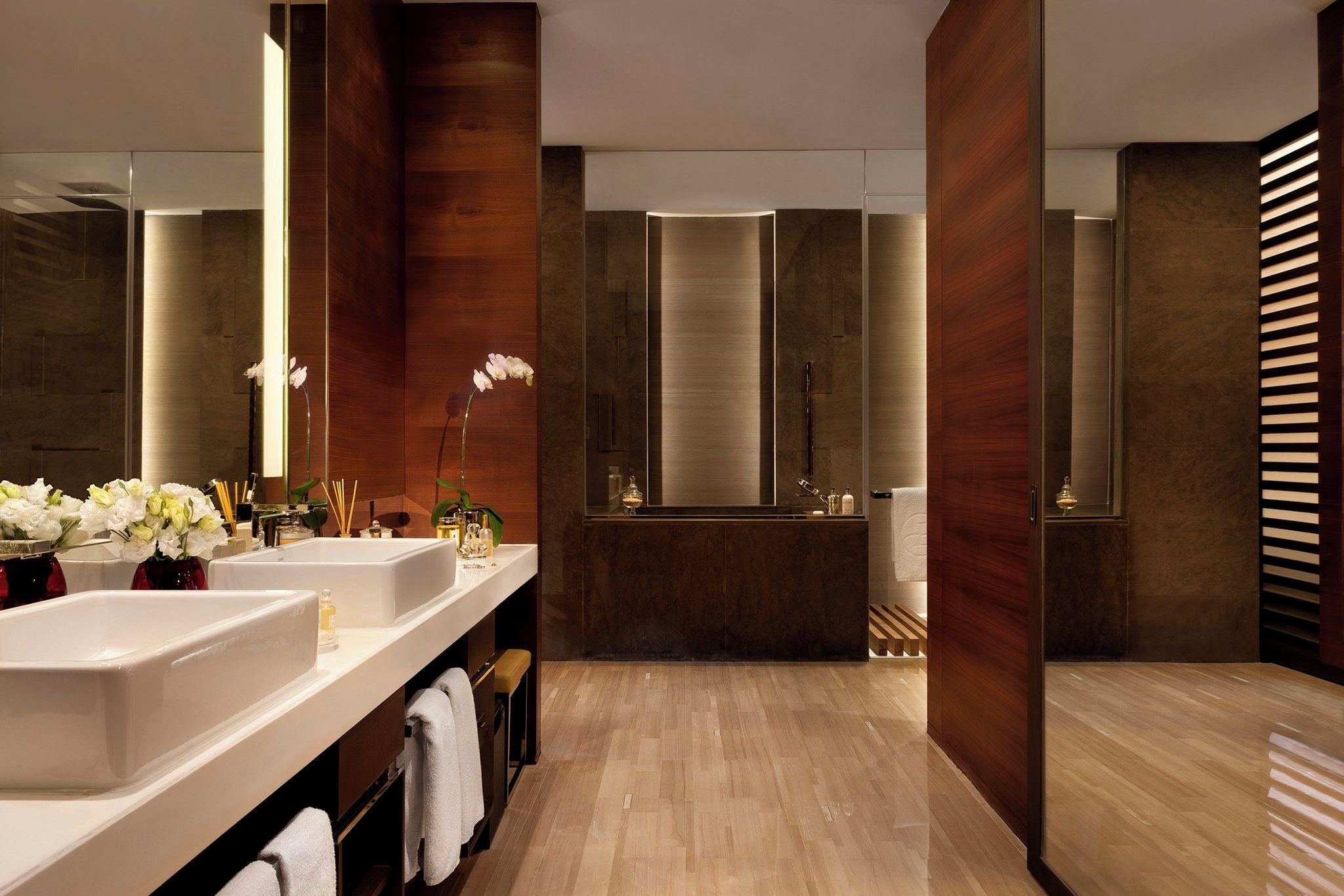 A modern bathroom with two sinks, a large mirror, and a bathtub.