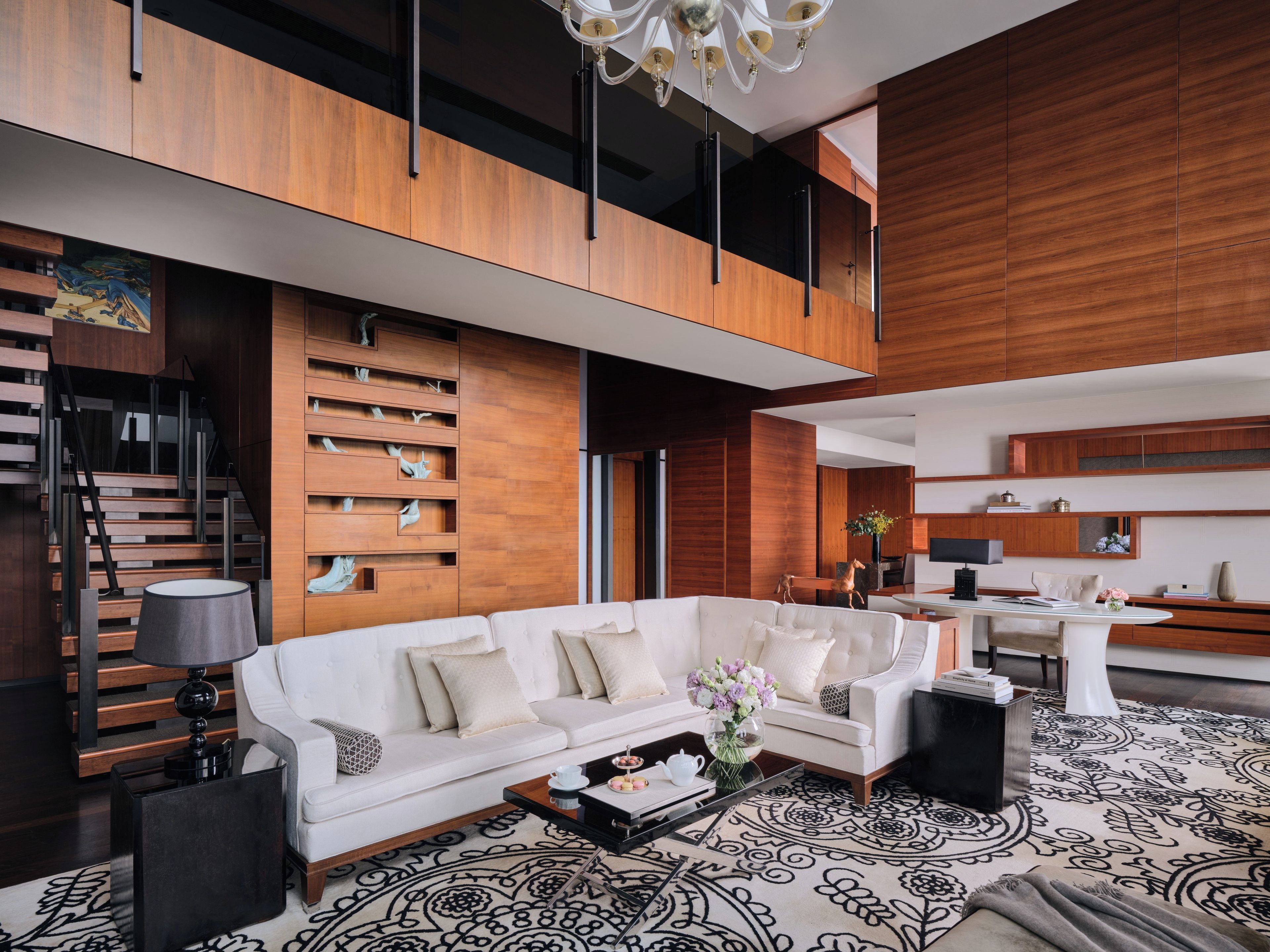A modern living room with a white sofa, a coffee table, and a patterned rug.
