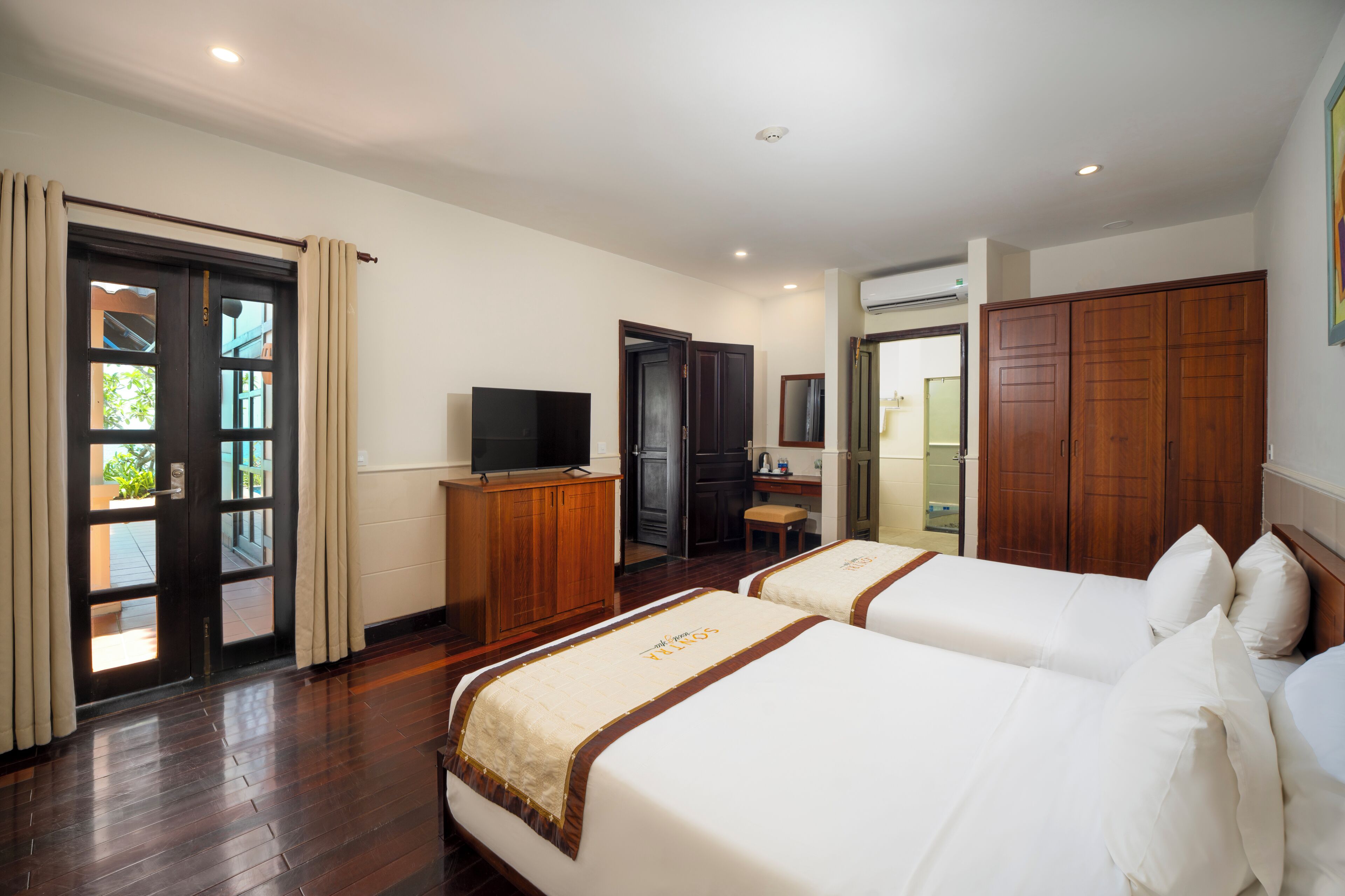 A hotel room with two beds, a television, a desk, and a wardrobe.