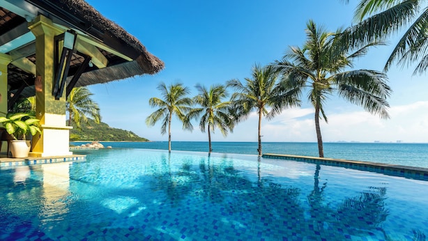 A clear blue infinity pool with palm trees and a view of the ocean. - Son Tra Resort (Da Nang)