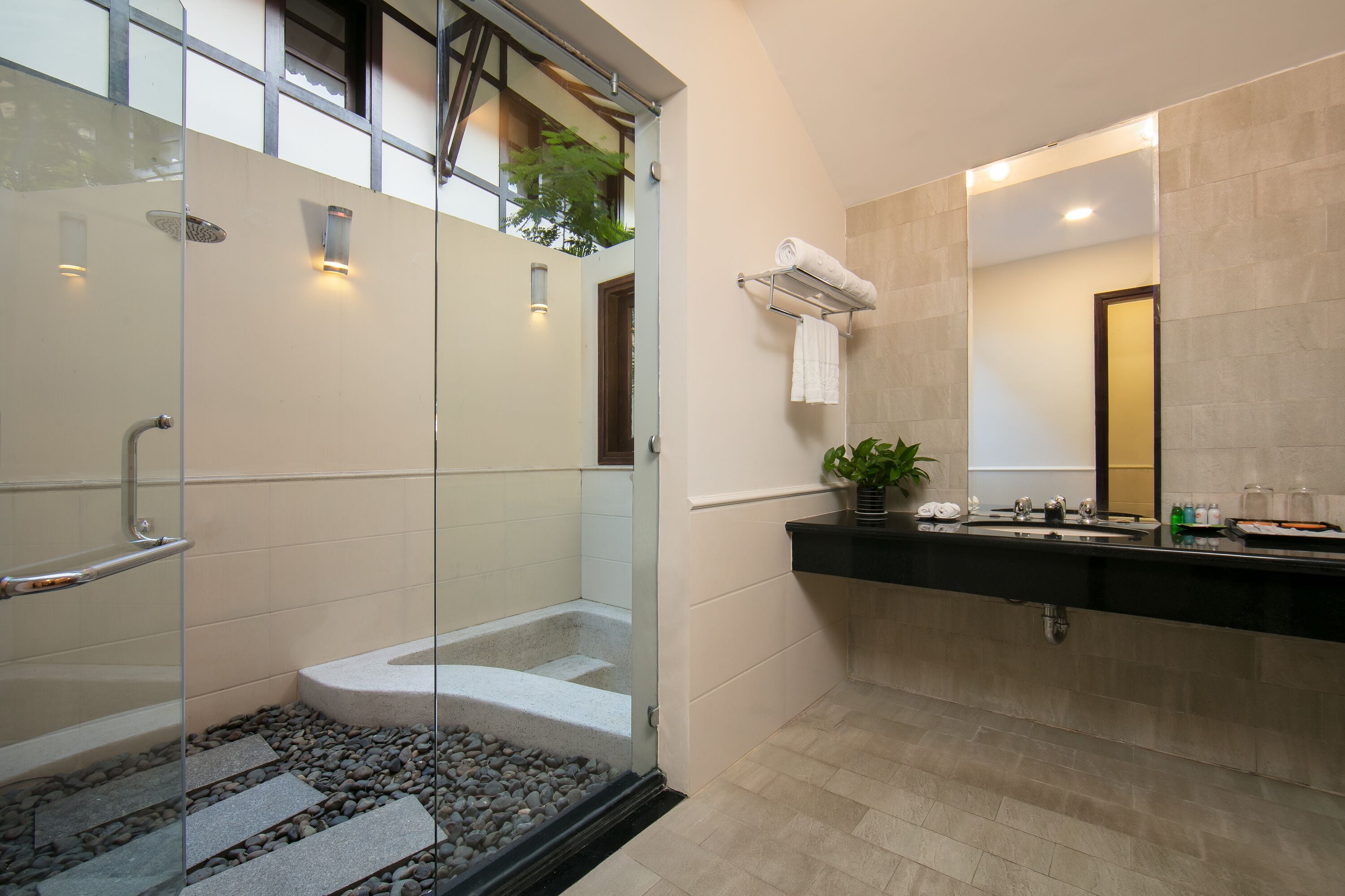 A modern bathroom with a glass-enclosed shower, a black countertop, and a large mirror.