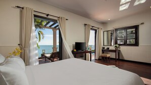 A bedroom with a large bed, a desk, a television, and a view of the ocean. - Son Tra Resort (Da Nang)