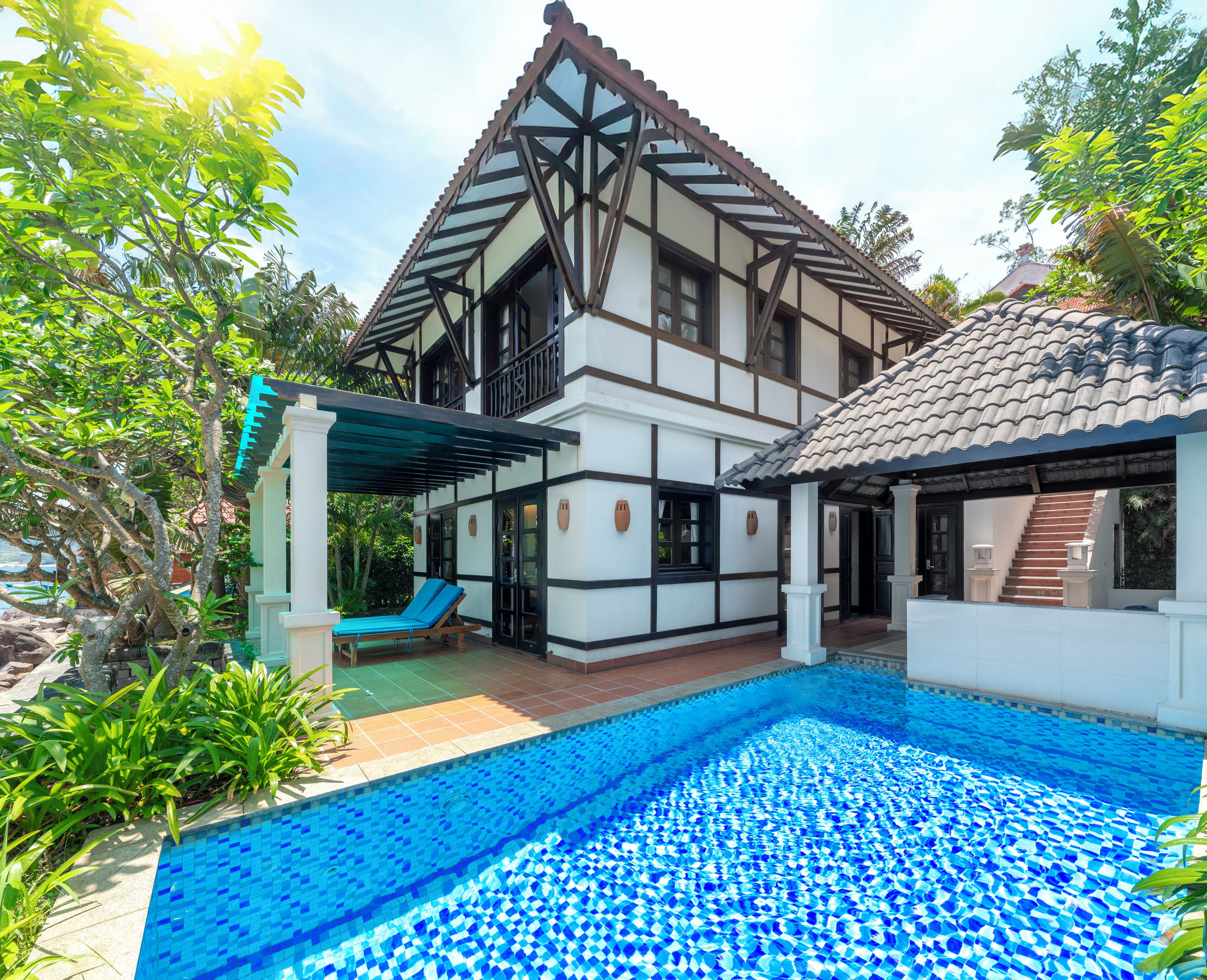 A two-story house with a swimming pool, a covered patio, and a garden.