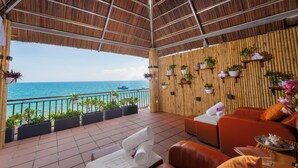 A covered outdoor area with a view of the sea, bamboo walls, and seating with towels. - Son Tra Resort (Da Nang)