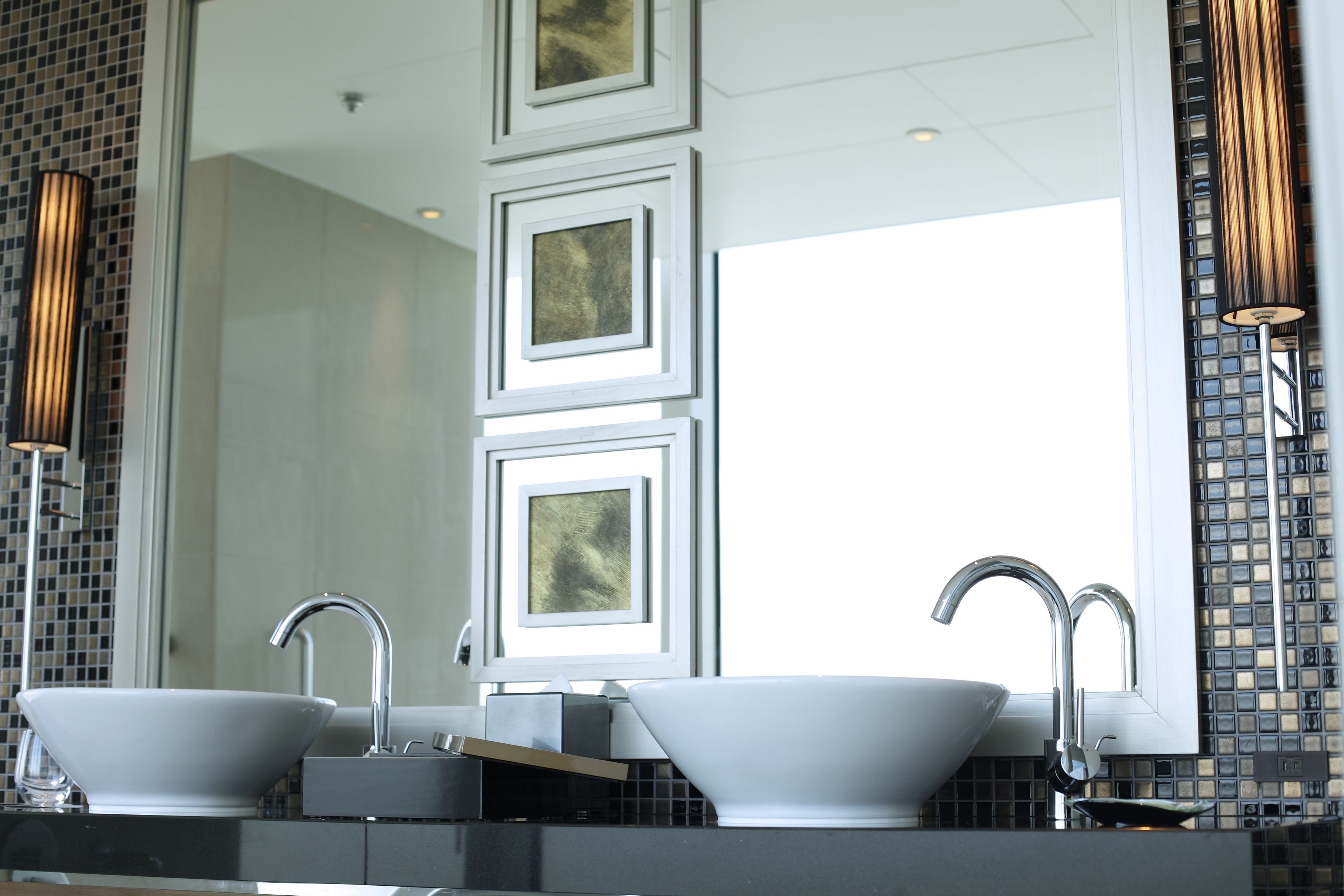 A modern bathroom with two sinks, a large mirror, and decorative wall tiles.