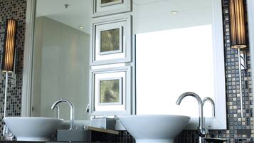 A modern bathroom with two sinks, a large mirror, and decorative wall tiles.