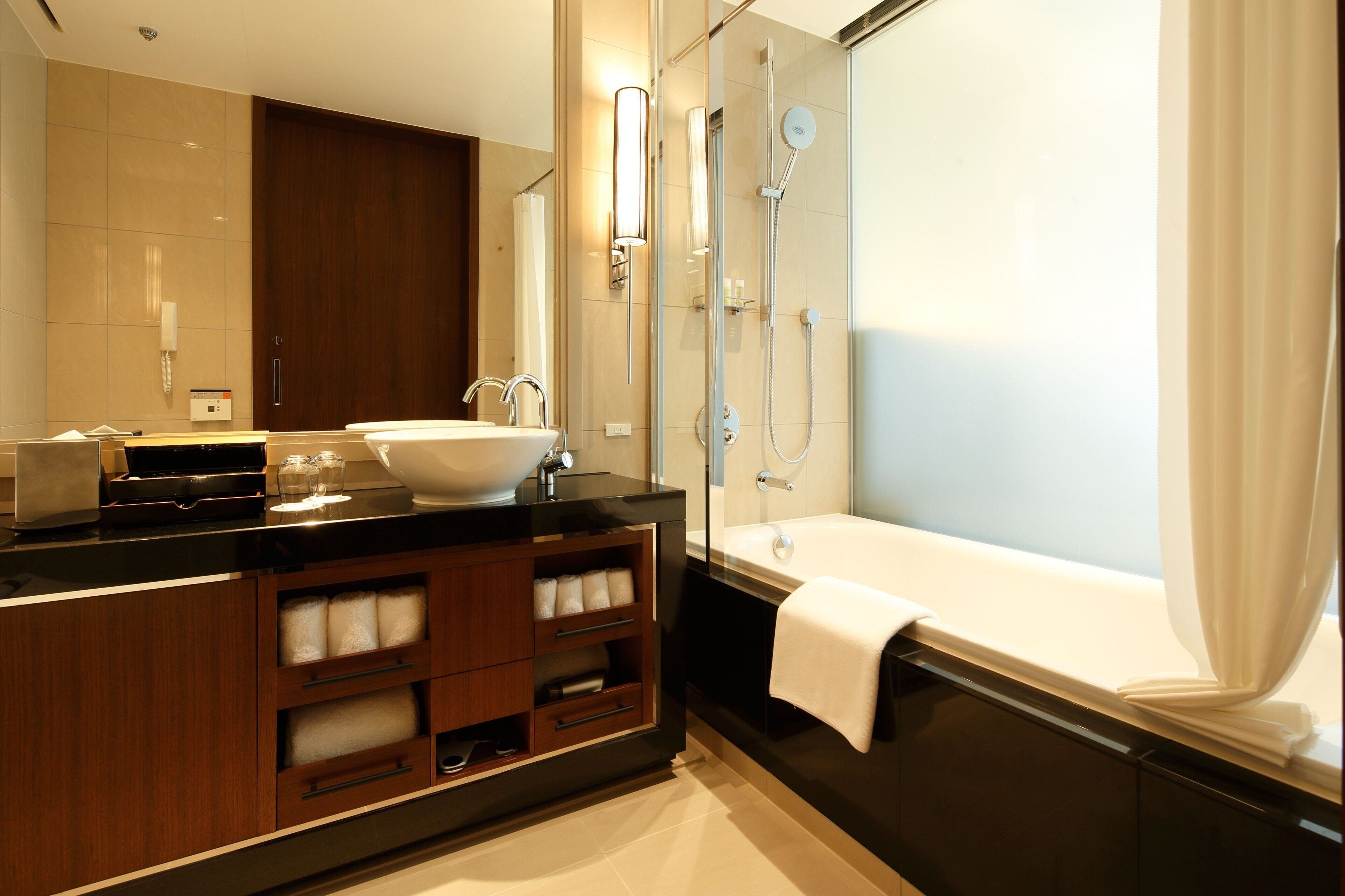 A modern bathroom with a large sink, mirror, and shower area.
