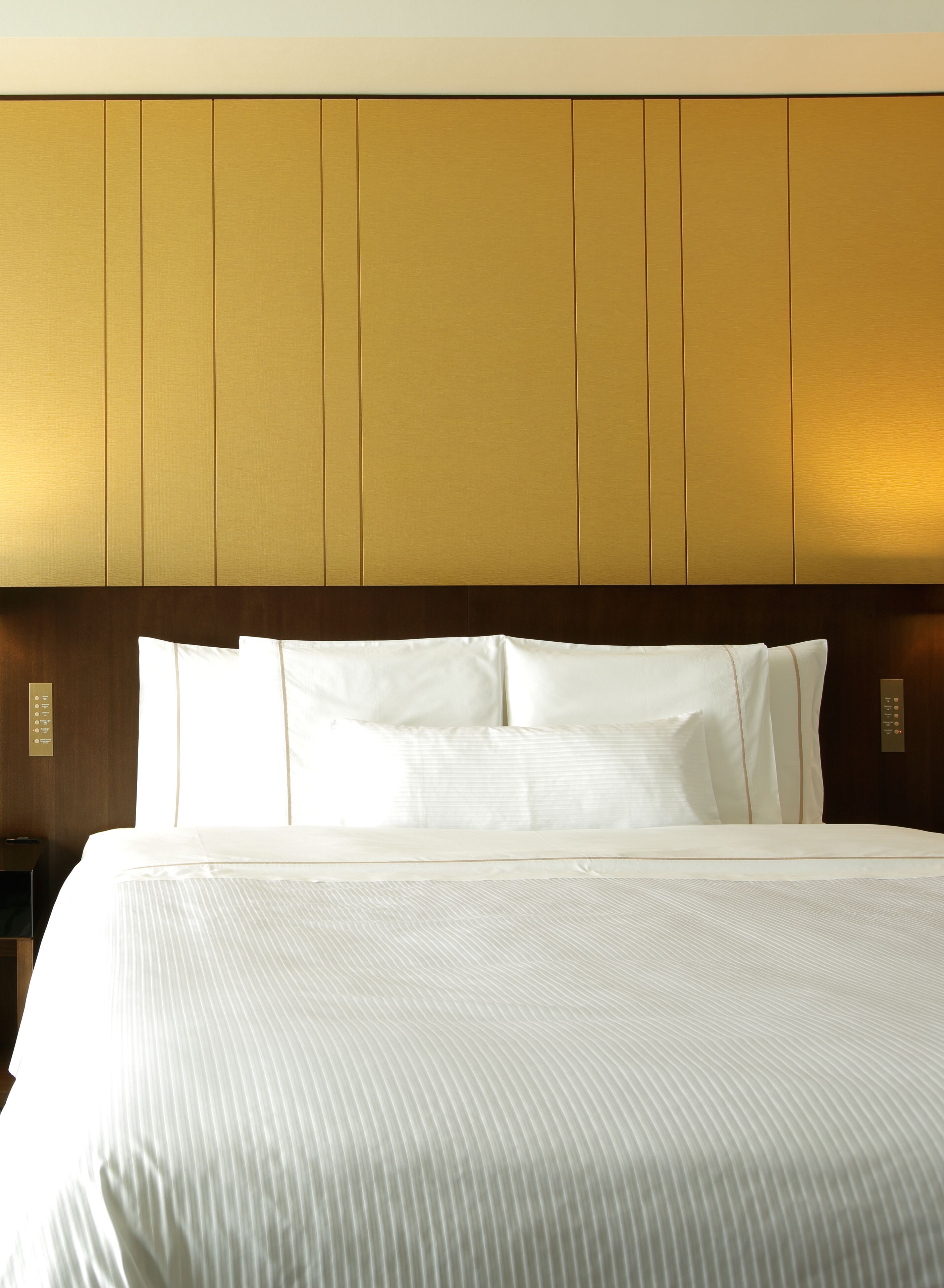 Una habitación de hotel con una cama grande, un cabecero de madera y una mesita de noche con una lámpara.