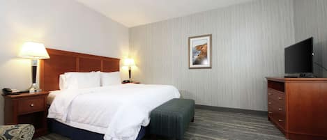 A hotel room with a bed, bedside lamps, a television, a desk, and a chair.