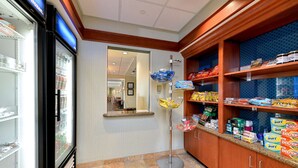Un hall d’hôtel doté d’une vitrine réfrigérée, d’un saladier en verre rempli d’en-cas et d’étagères garnies de divers produits.