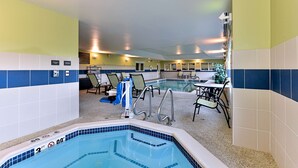 A swimming pool area with lounge chairs, a hot tub, and a dining area.