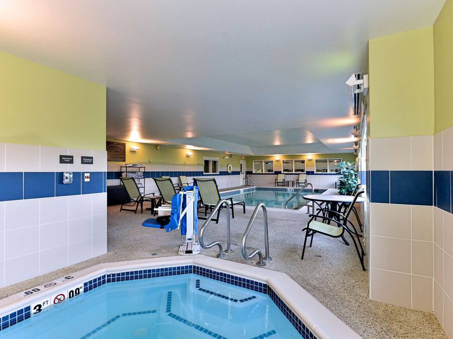 Un espace piscine comprenant des chaises longues, un jacuzzi et un coin repas.