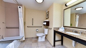 A bathroom with a shower, toilet, sink, and mirror.