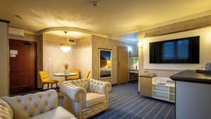 A hotel room with a seating area, a flat-screen TV, a small table, and a door. - Hotel Diament Vacanza Siemianowice Slaskie (Siemianowice Slaskie)