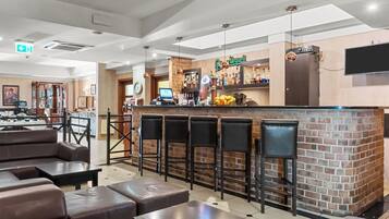A bar area with a brick counter, multiple stools, and a seating area with tables and chairs.
