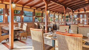 An outdoor restaurant with wooden beams, wicker furniture, and large windows. - Hotel Diament Vacanza Siemianowice Slaskie (Siemianowice Slaskie)