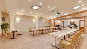 A conference room with long tables and chairs, a brick accent wall, and recessed lighting.