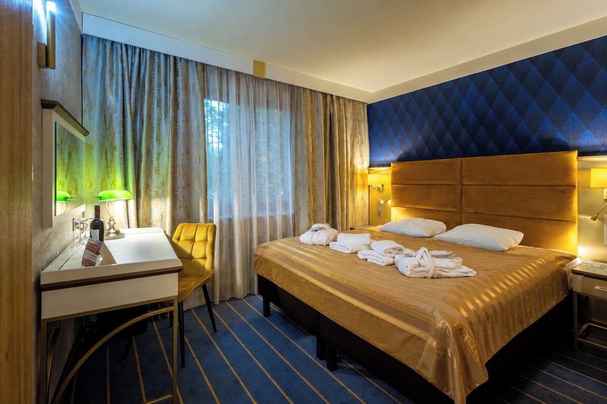 Ein Hotelzimmer mit Bett, Schreibtisch, Stuhl, Spiegel und Nachttisch.
