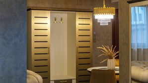 A hotel room with a walk-in closet, a dining area with a table and chairs, and a chandelier. - Hotel Diament Vacanza Siemianowice Slaskie (Siemianowice Slaskie)