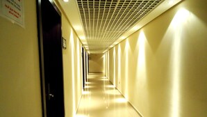 A long, well-lit hallway with a tiled floor and a ceiling with a grid pattern. - Al Jazira Club Hotel (Abu Dhabi)