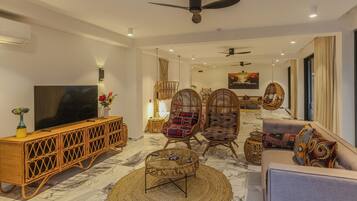 A modern living room with a TV, wicker furniture, and a ceiling fan.