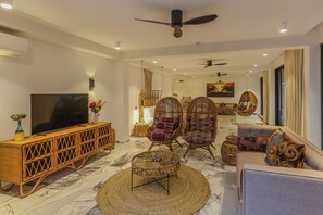 A modern living room with a TV, wicker furniture, and a ceiling fan. - Z Hotel & Z2 Hotel (Nungwi)