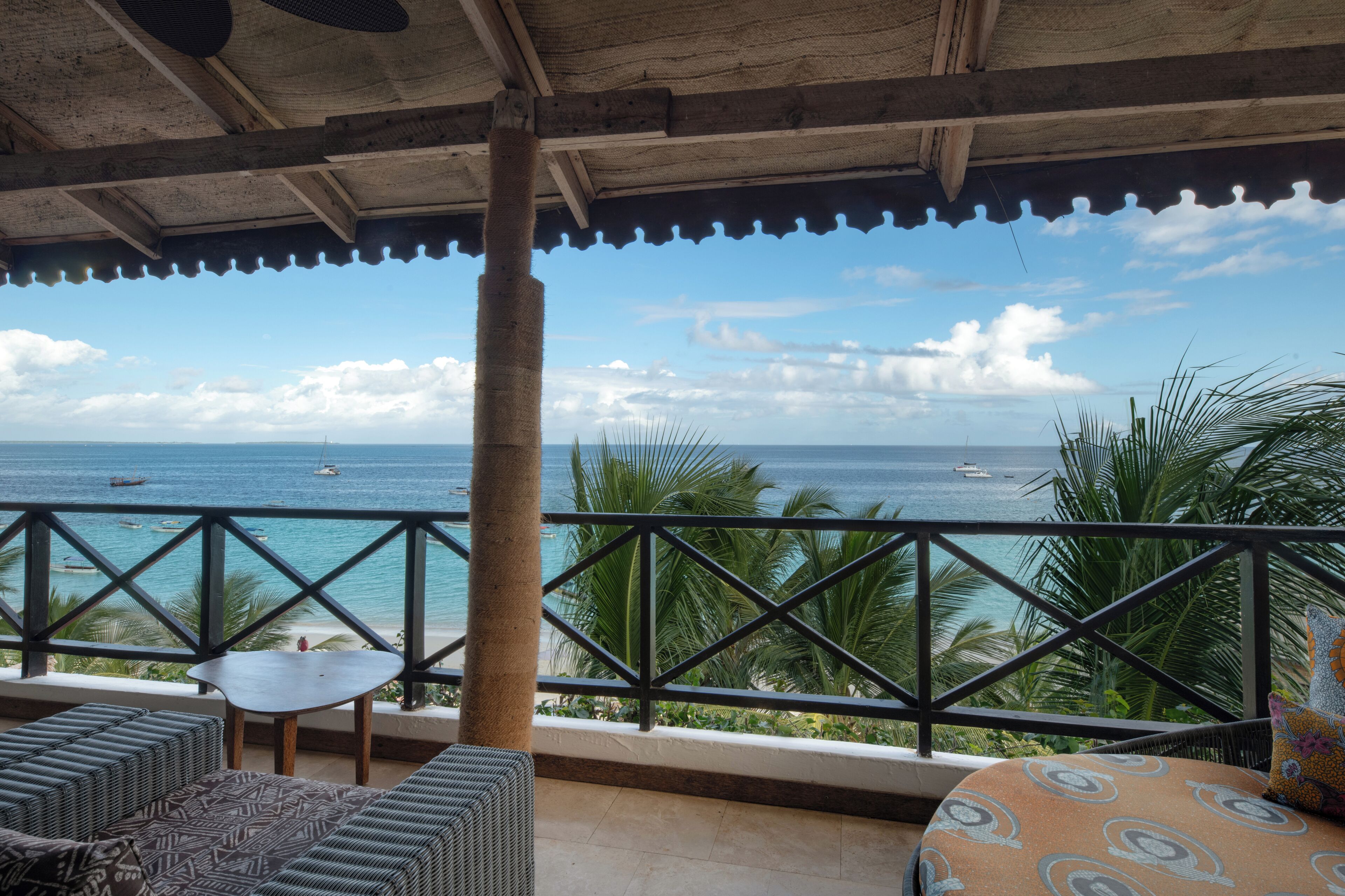 Un espace extérieur abrité, aménagé avec des sièges, et offrant une vue sur la mer et les bateaux.