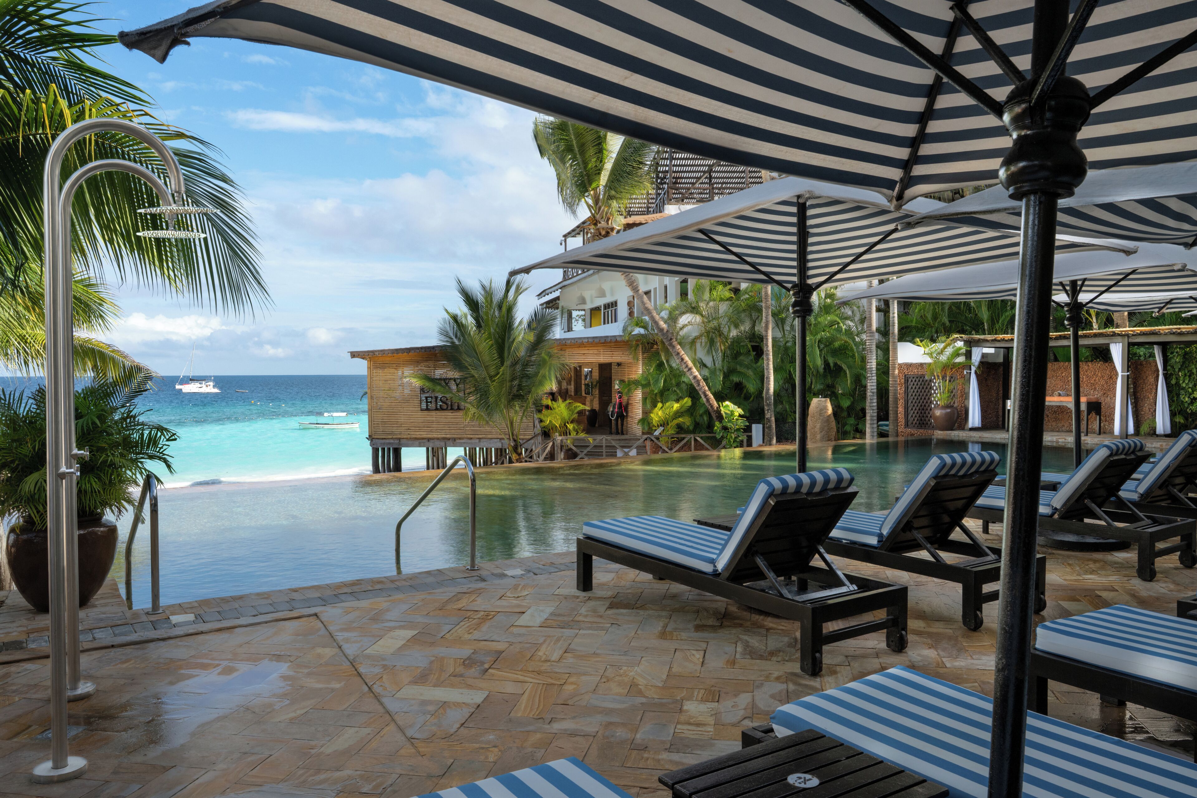 A poolside area with lounge chairs, umbrellas, and a view of the ocean.