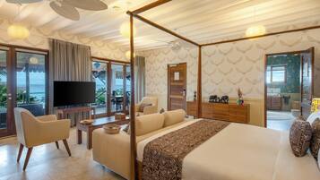 A spacious bedroom with a four-poster bed, a television, and a balcony with a view of the sea.