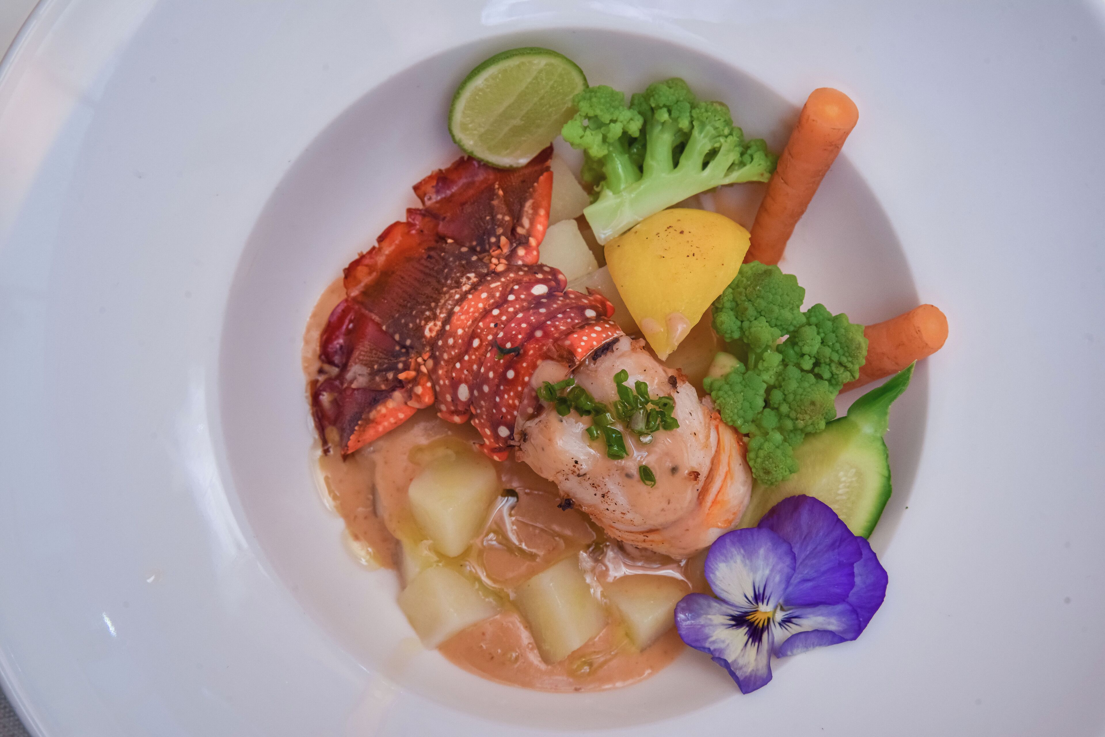 A seafood dish with lobster, shrimp, and vegetables on a plate.