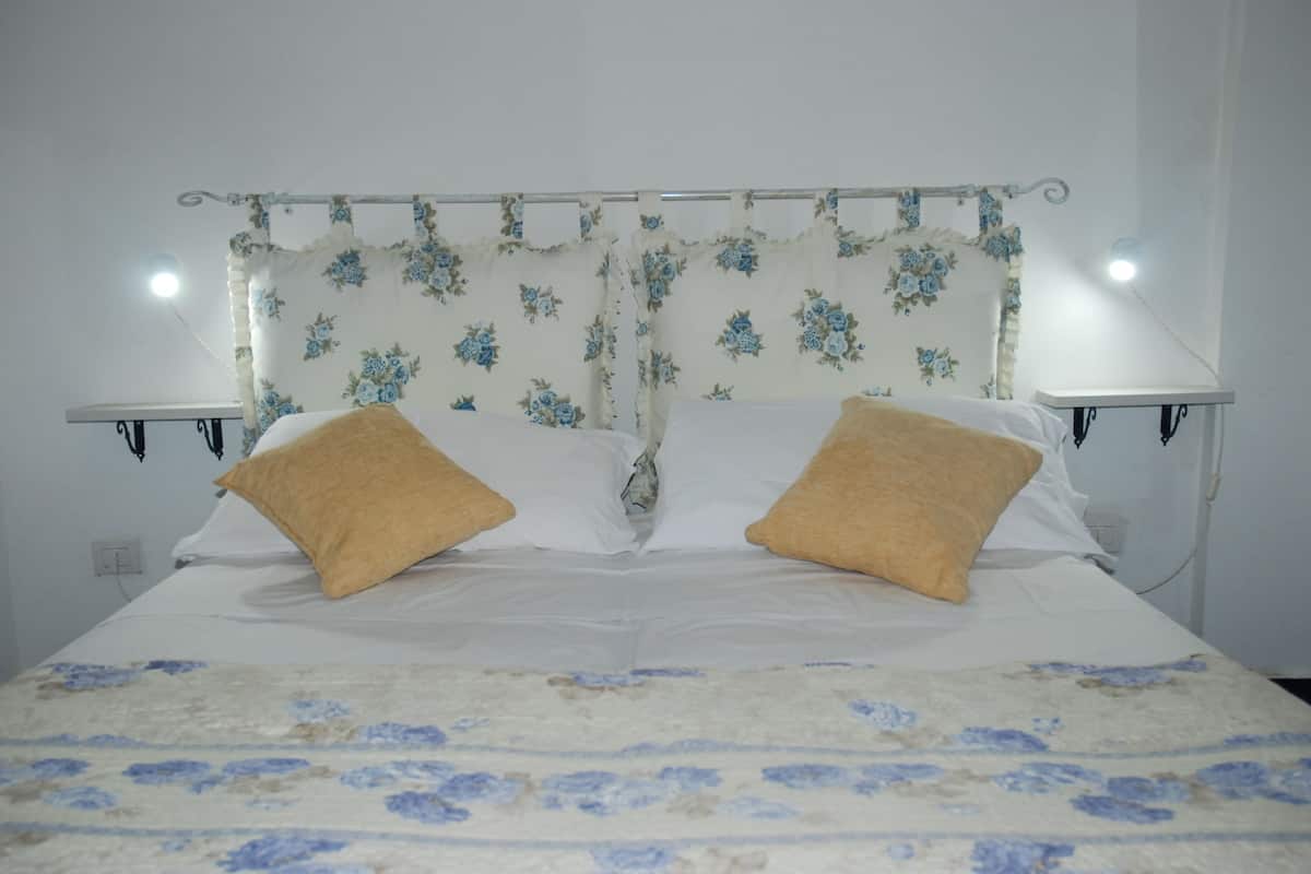A bed with a floral-patterned headboard, two bedside tables with lamps, and a floral-patterned bedspread.