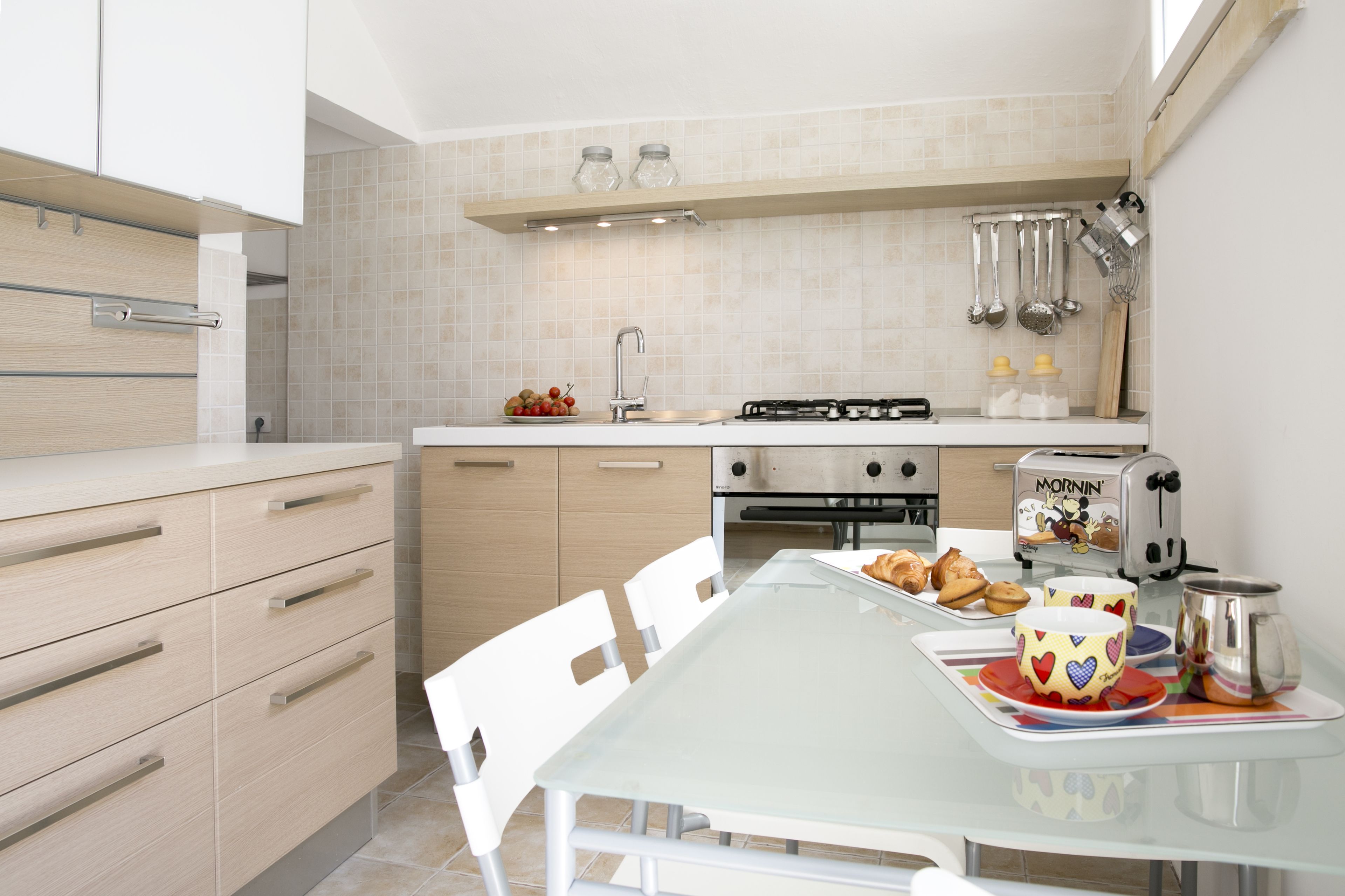 Una cocina moderna con estufa a gas, tostadora y alacenas blancas.